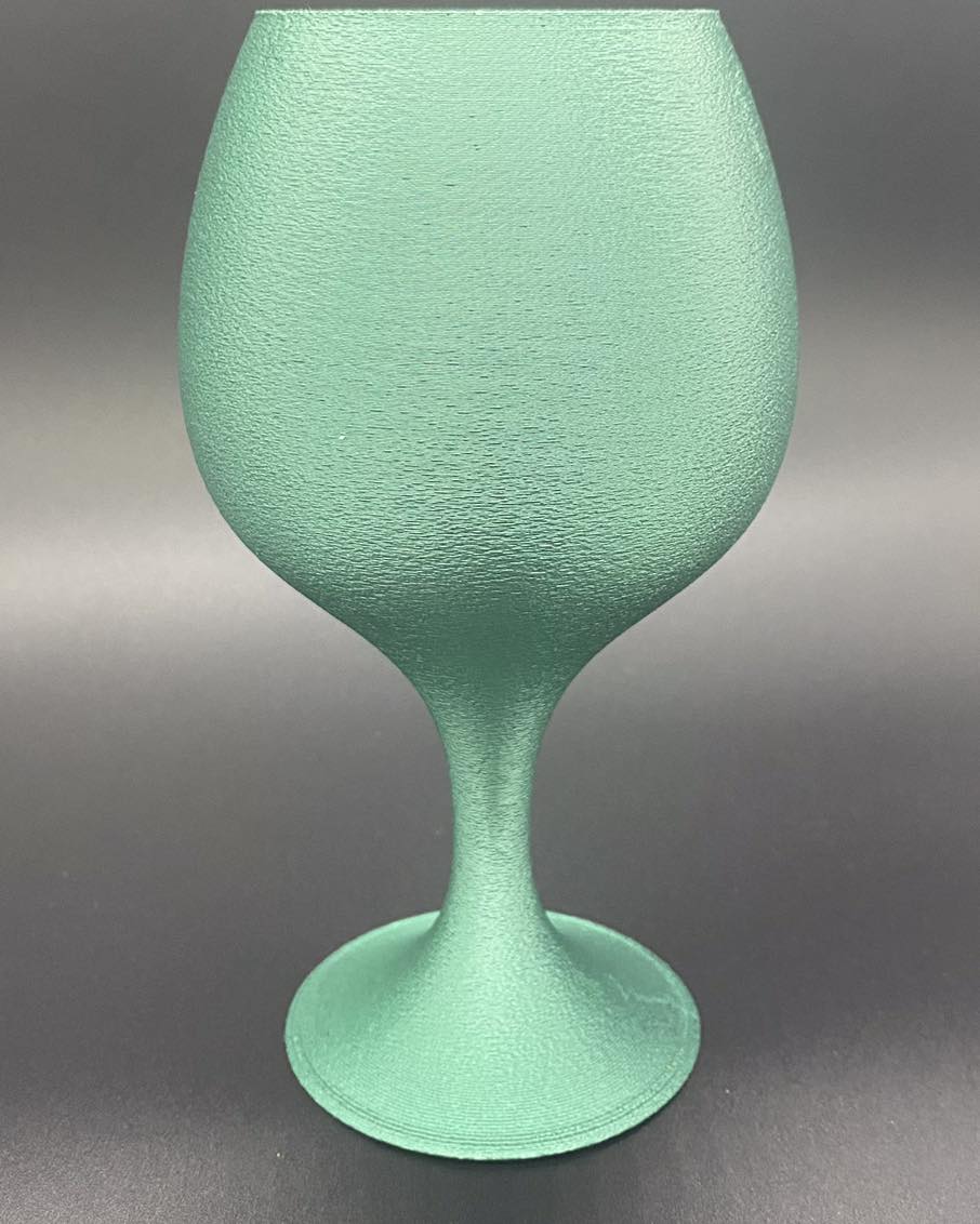 Metal look Green textured wine glass on a gray background